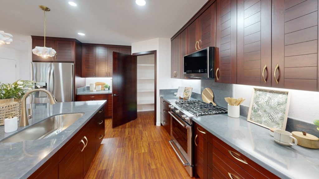 Remodeled kitchen with dark wood cabinetry, stainless appliances, and walk-in pantry by Atlas Construction